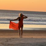 Charla Hathaway on a tropical beach at sunset with red fabric.